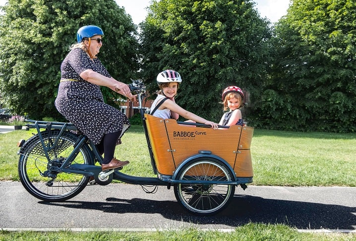 Woman riding a bike with two children in front child seating